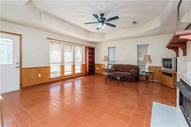 living area featuring brick floor, wainscoting, and a raised ceiling