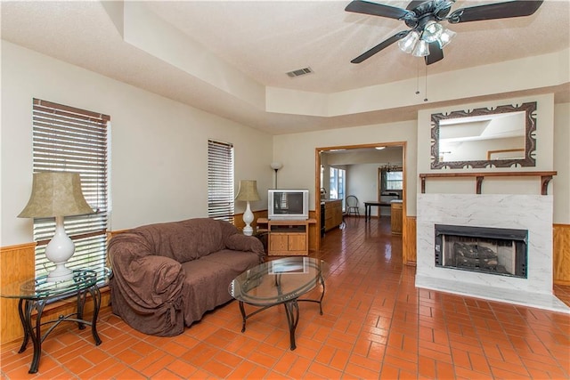 living area with brick floor, plenty of natural light, a high end fireplace, and visible vents