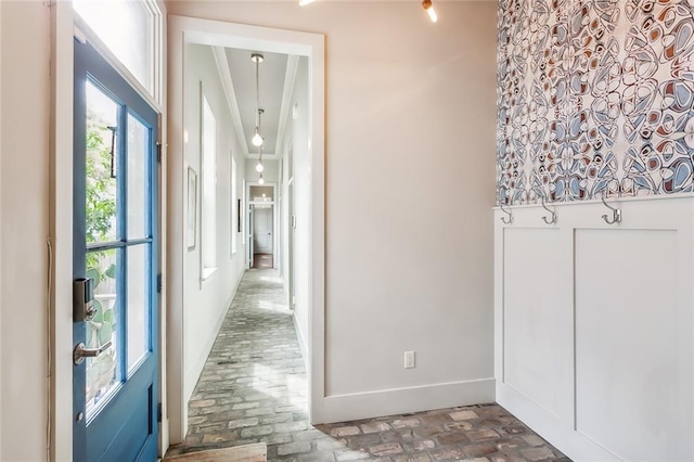 hall with brick floor, baseboards, and crown molding