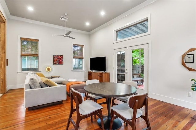 dining area with light wood-type flooring, baseboards, visible vents, and crown molding