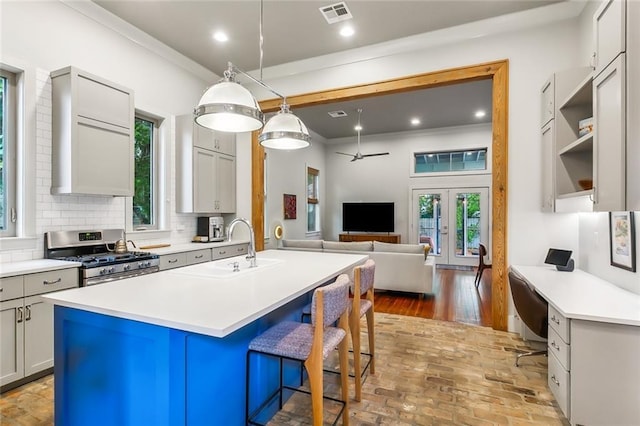 kitchen with stainless steel gas range, a sink, decorative backsplash, and ornamental molding