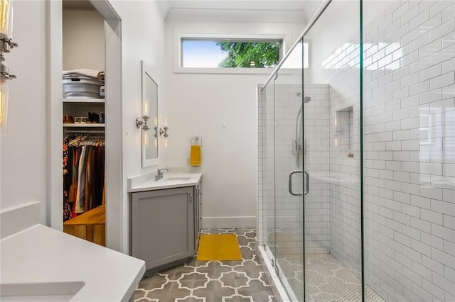 full bath featuring a stall shower, a walk in closet, vanity, and crown molding