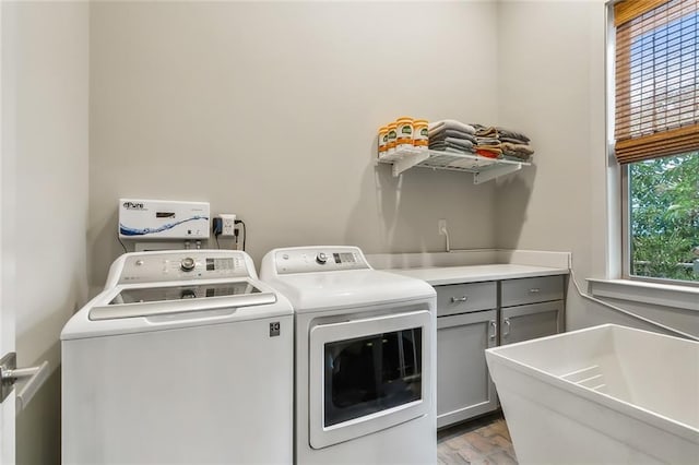 clothes washing area with wood finished floors, cabinet space, and washer and dryer