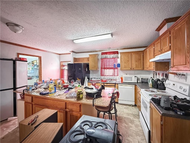 kitchen featuring a textured ceiling, under cabinet range hood, white appliances, brown cabinetry, and crown molding