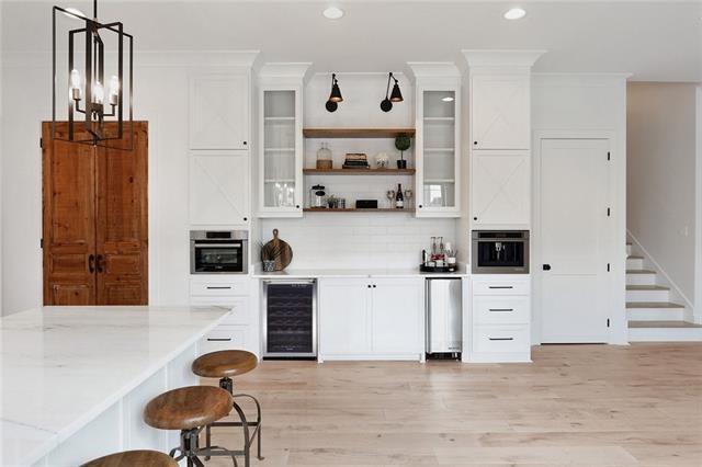 bar with beverage cooler, pendant lighting, crown molding, and oven