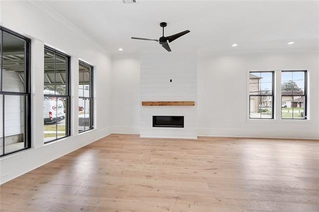 unfurnished living room with light wood-style floors, a fireplace, crown molding, and recessed lighting