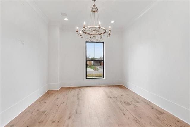 empty room featuring ornamental molding, light wood-type flooring, a notable chandelier, and baseboards