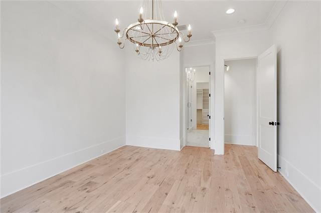 spare room featuring recessed lighting, baseboards, ornamental molding, light wood finished floors, and an inviting chandelier