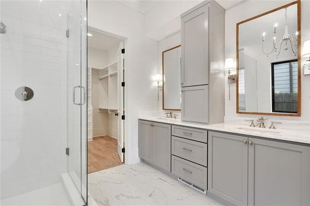 full bath with double vanity, a stall shower, marble finish floor, and a sink