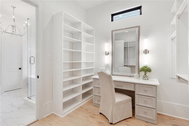 bathroom featuring a stall shower, a notable chandelier, and wood finished floors