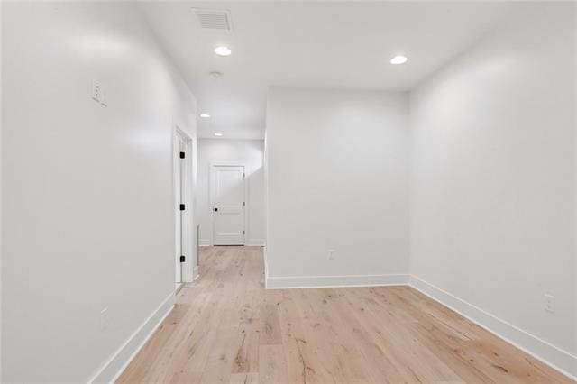 hallway featuring light wood-style flooring, visible vents, baseboards, and recessed lighting