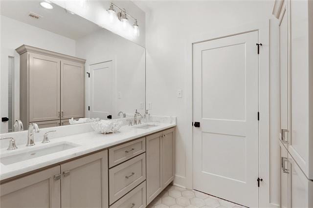 bathroom with visible vents, a sink, and double vanity