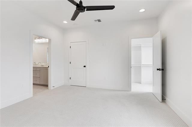 unfurnished bedroom with a spacious closet, recessed lighting, visible vents, and light colored carpet