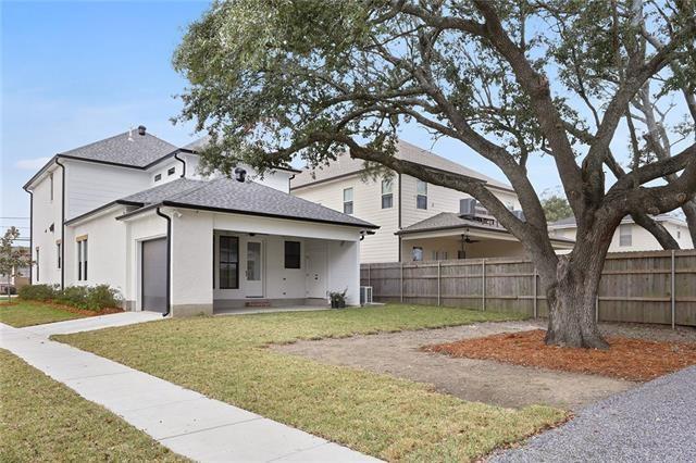 rear view of house featuring a shingled roof, fence, an attached garage, and a lawn