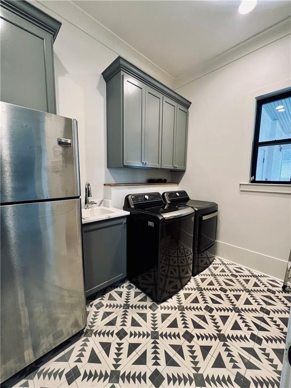 washroom featuring cabinet space, baseboards, washing machine and clothes dryer, crown molding, and a sink