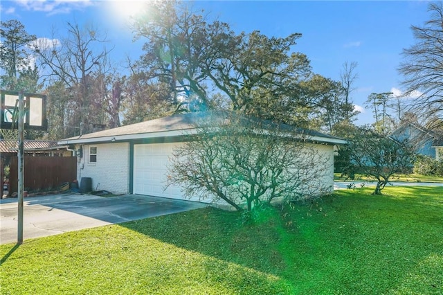 view of home's exterior featuring driveway, a garage, fence, a yard, and brick siding