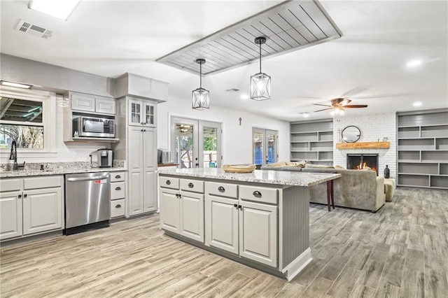 kitchen with a brick fireplace, gray cabinetry, appliances with stainless steel finishes, and french doors