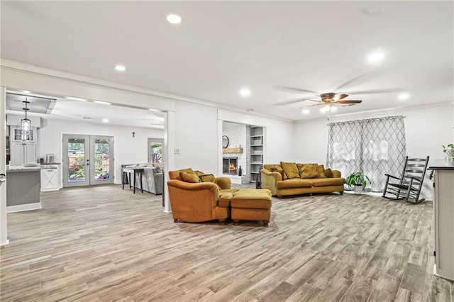 living room with light wood-type flooring, french doors, a fireplace, and recessed lighting