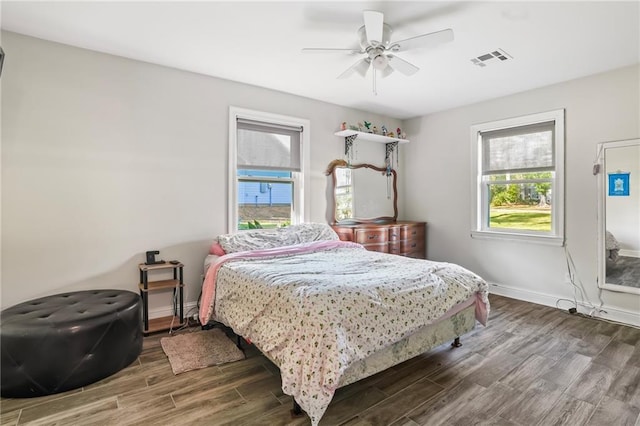 bedroom featuring a ceiling fan, visible vents, baseboards, and wood finished floors