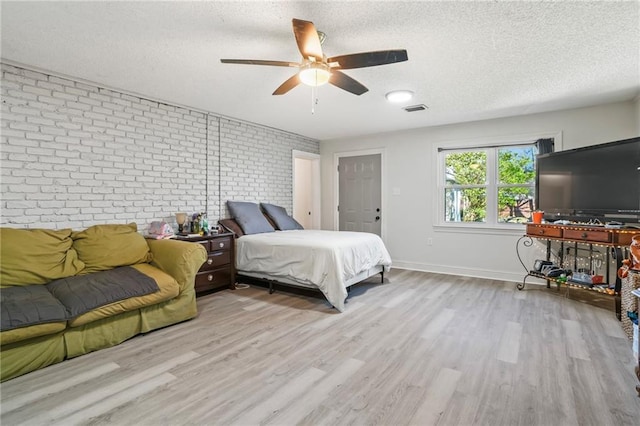 bedroom featuring baseboards, visible vents, brick wall, wood finished floors, and a textured ceiling