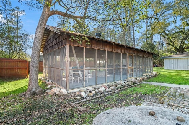 view of side of property with a yard, a sunroom, and fence