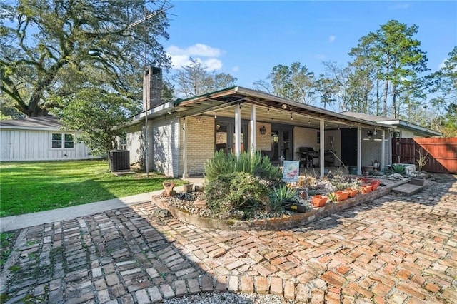 rear view of house featuring brick siding, a lawn, a patio, and fence