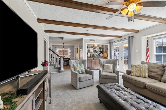 living area with stairs, beamed ceiling, french doors, and light colored carpet