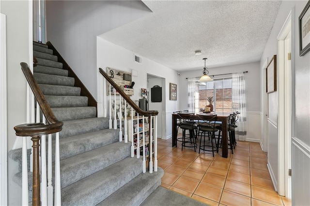 dining area featuring stairs, visible vents, a textured ceiling, and light tile patterned floors