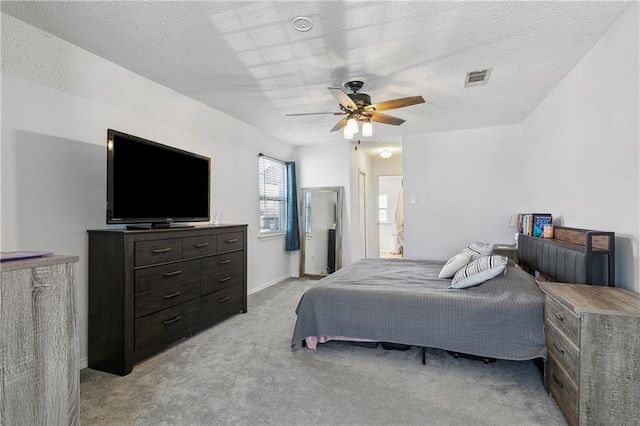 bedroom with a ceiling fan, visible vents, a textured ceiling, and light colored carpet