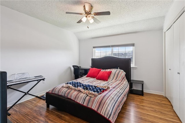 bedroom featuring baseboards, ceiling fan, wood finished floors, a textured ceiling, and a closet