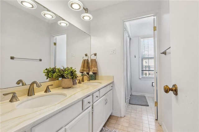 full bathroom featuring double vanity, tile patterned flooring, baseboards, and a sink