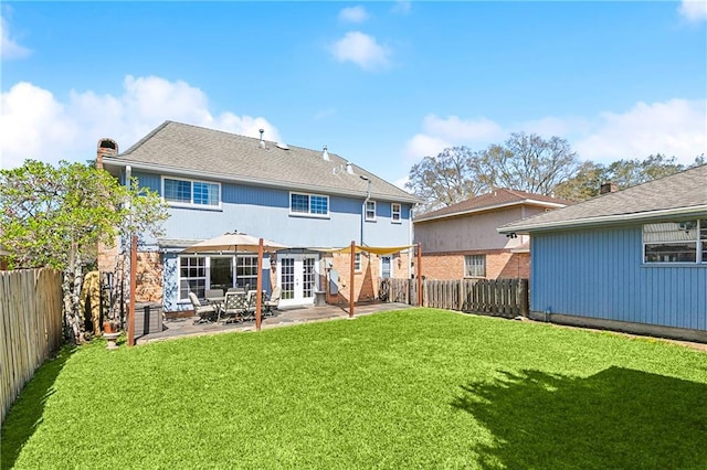 back of house with a patio, a lawn, a chimney, and a fenced backyard