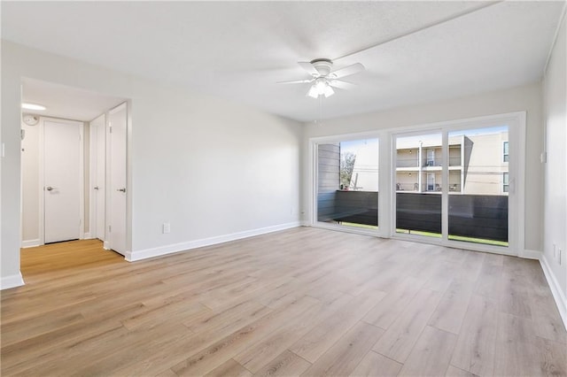 spare room featuring light wood-style floors, baseboards, and a ceiling fan