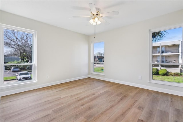 empty room featuring a ceiling fan, baseboards, and wood finished floors