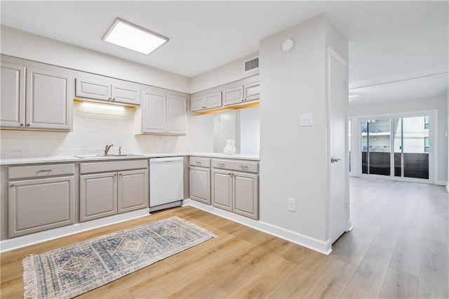 kitchen with gray cabinetry, a sink, light countertops, dishwasher, and light wood finished floors