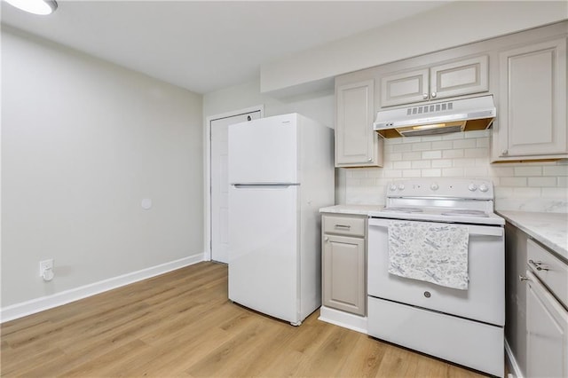 kitchen with under cabinet range hood, white appliances, baseboards, decorative backsplash, and light wood finished floors