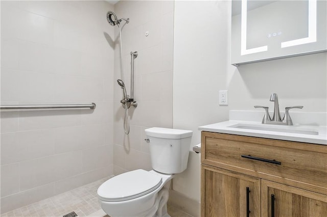 full bathroom featuring a tile shower, vanity, and toilet