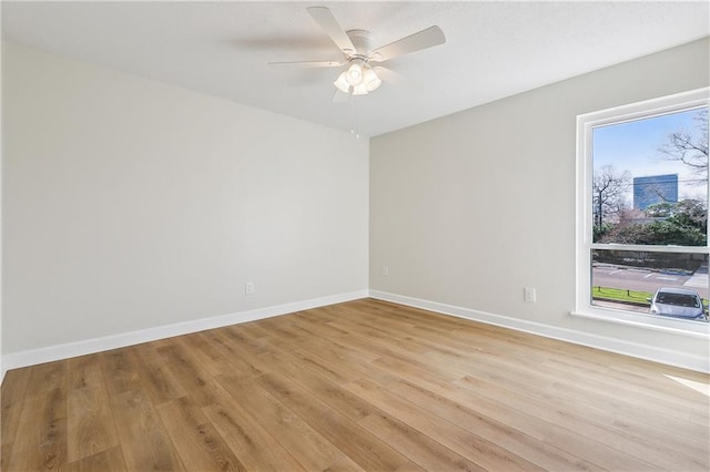 unfurnished room featuring light wood-style floors, a wealth of natural light, and baseboards