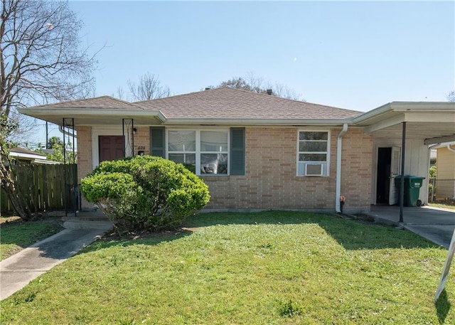 view of front facade with brick siding, a carport, a front yard, and fence