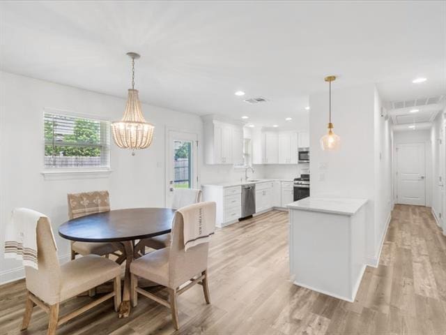 dining space featuring light wood-type flooring, visible vents, and baseboards