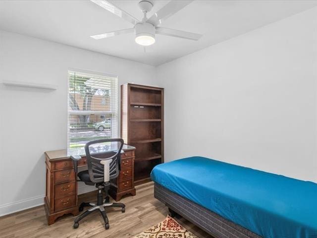 bedroom with ceiling fan, wood finished floors, and baseboards