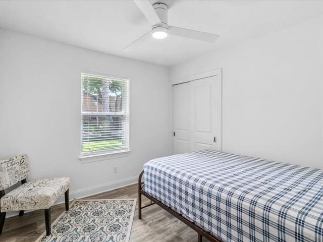 bedroom with ceiling fan, a closet, baseboards, and wood finished floors