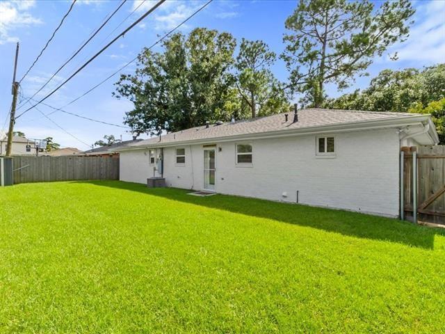 back of house with cooling unit, fence, and a lawn