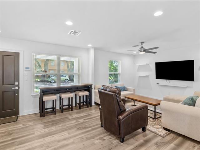 living area with light wood-type flooring, visible vents, and recessed lighting