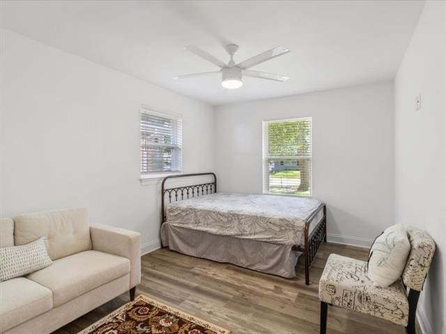 bedroom with multiple windows, wood finished floors, and baseboards