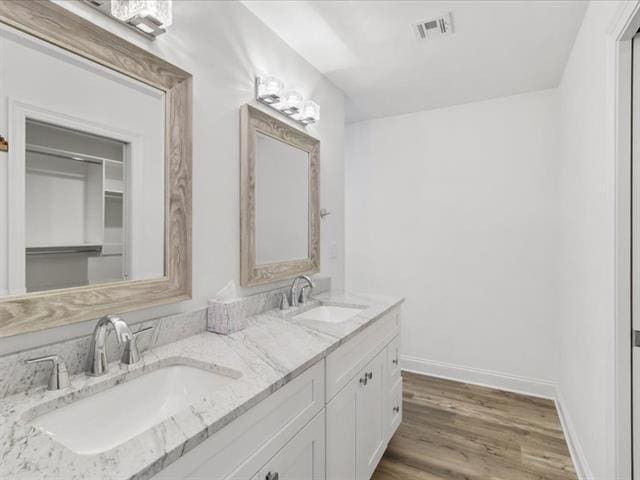 bathroom featuring wood finished floors, a sink, visible vents, and baseboards