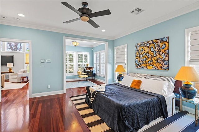 bedroom featuring baseboards, wood finished floors, visible vents, and crown molding