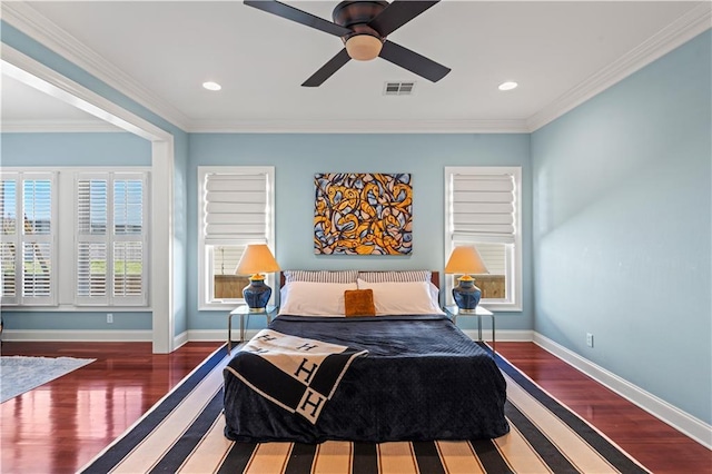 bedroom with ornamental molding, visible vents, baseboards, and wood finished floors