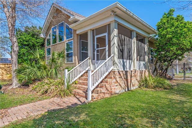 view of front facade with a sunroom, fence, and a front yard