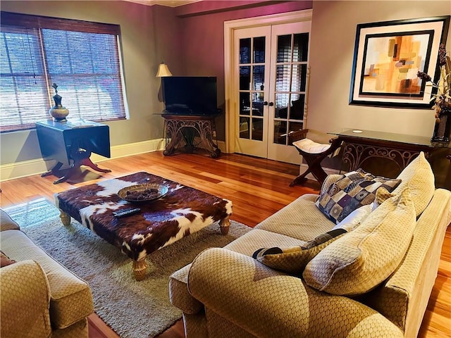 living area with french doors, baseboards, and wood finished floors